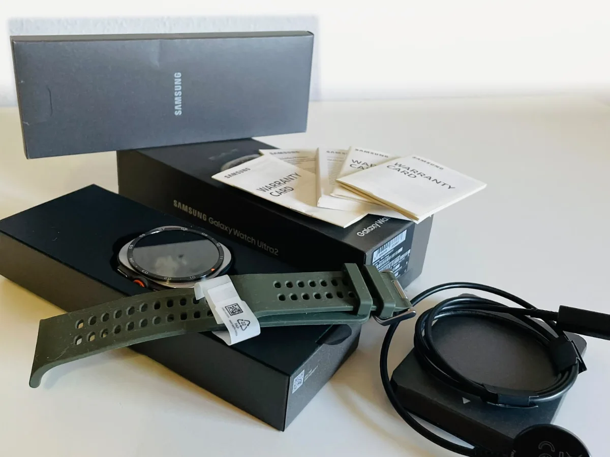 Otra vista del contenido de la caja del Samsung Galaxy Watch Ultra2: reloj en su bandeja, correa, cargador y tarjetas de garantía