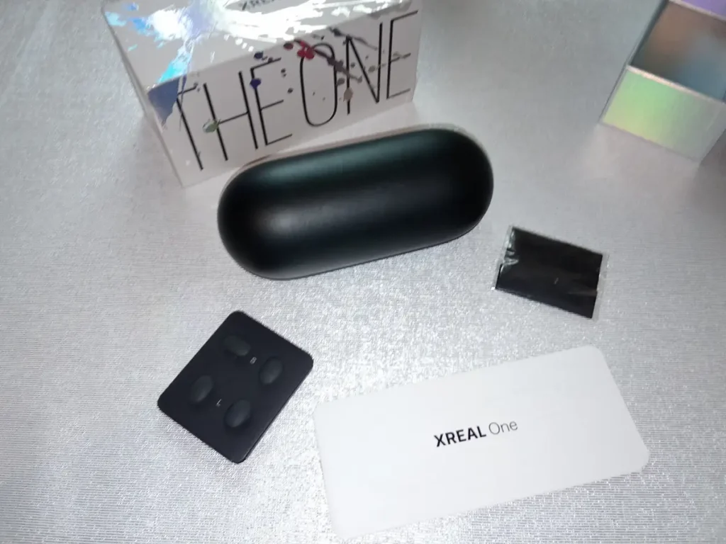 Contenido de la caja de las XREAL One: estuche rígido, paño de limpieza, almohadillas nasales y tarjeta, junto a la caja The One. Unidad analizada por Rankiko.