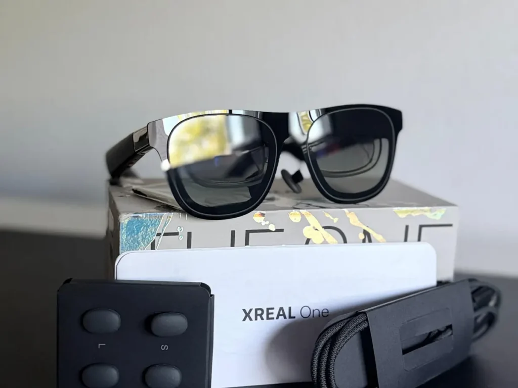 Gafas XREAL One sobre su caja, con almohadillas nasales, tarjeta y cable USB-C trenzado.